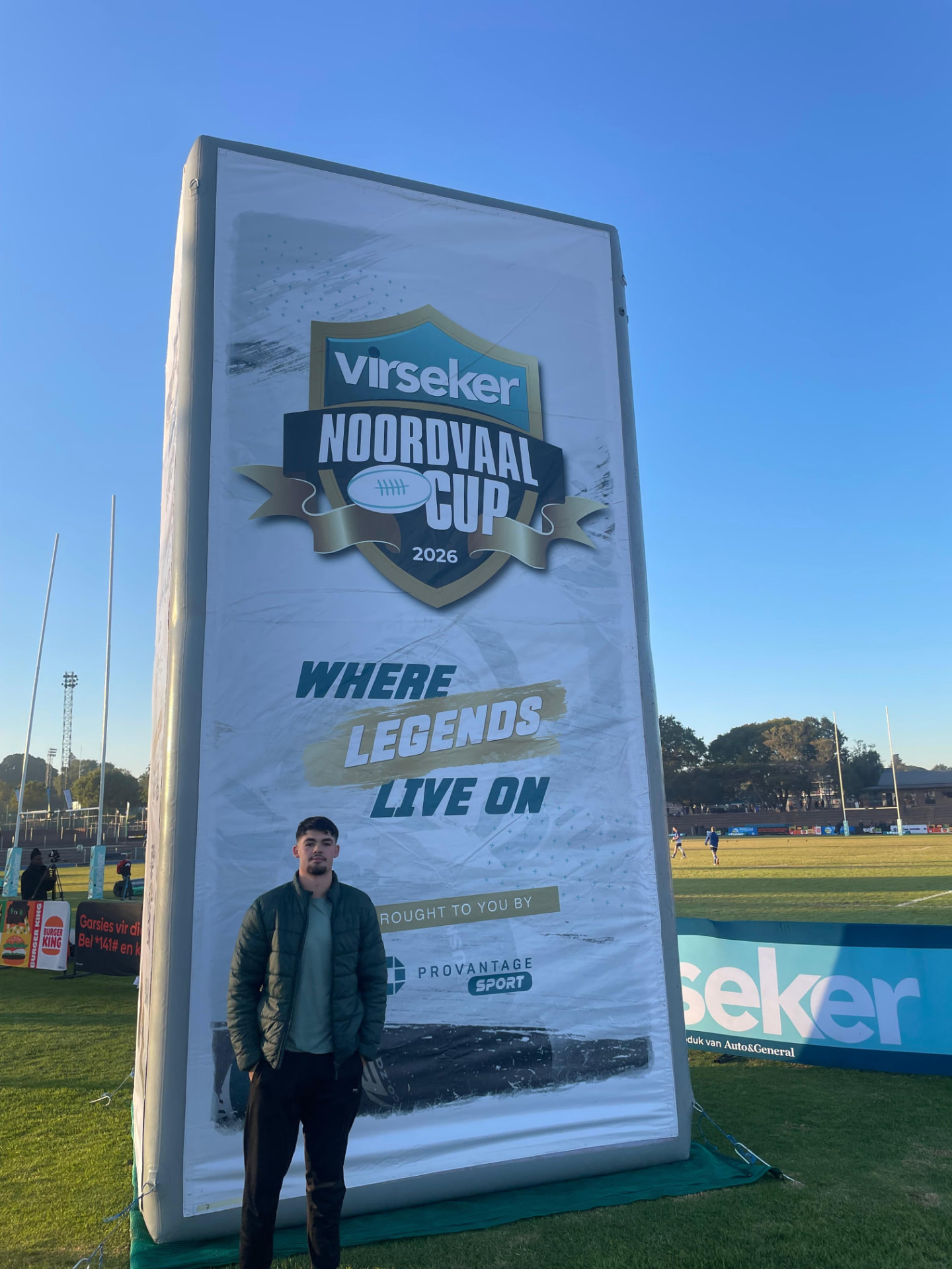 Man standing beside a towering inflatable Noordvaal Cup billboard